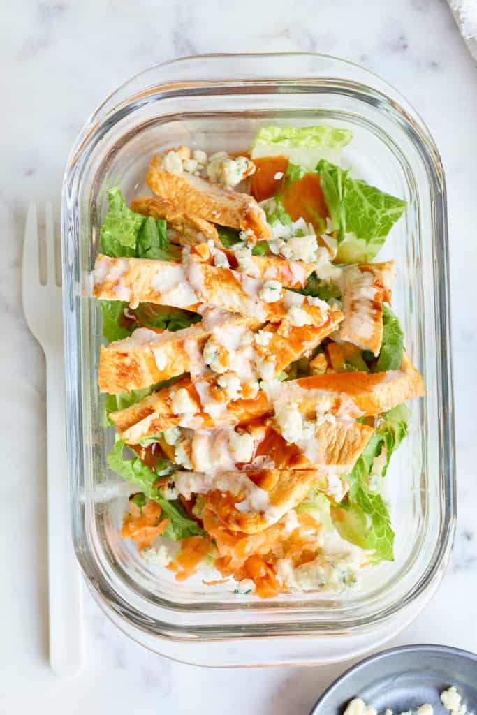buffalo chicken salad in meal prep bowl with dressing on top